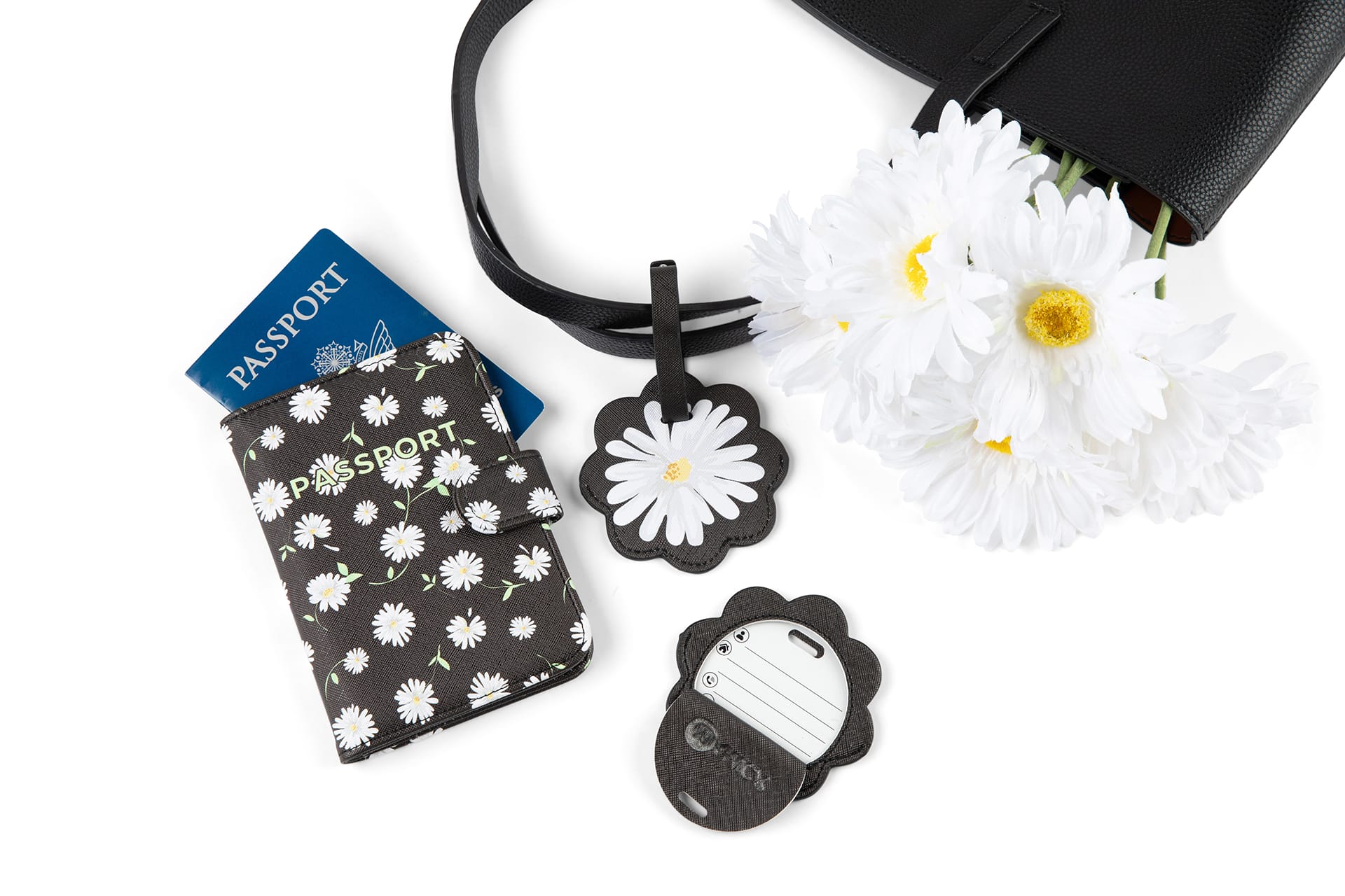 A black passport case with daisy motif is on left. Two daisy-shaped luggage tags are on right.