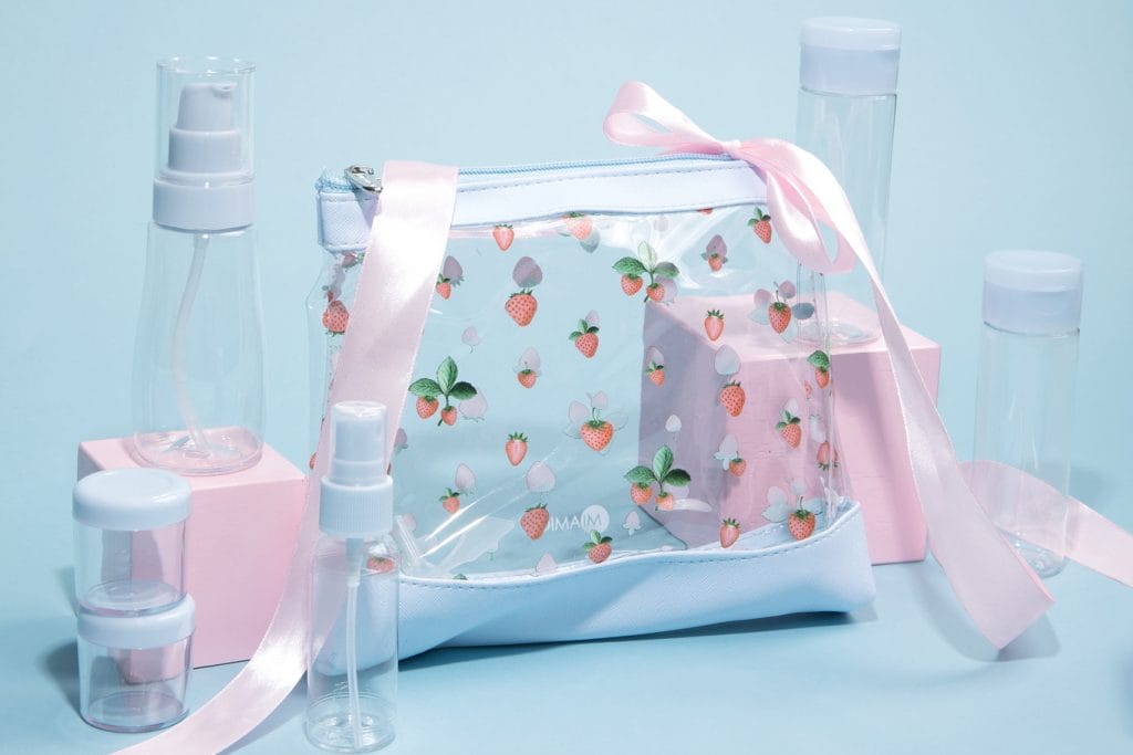 Clear bottle set with strawberry print design features soft blue borders. Powder blue caps cover jars, bottles and a moisturizer pump dispenser for your packing and organization needs.