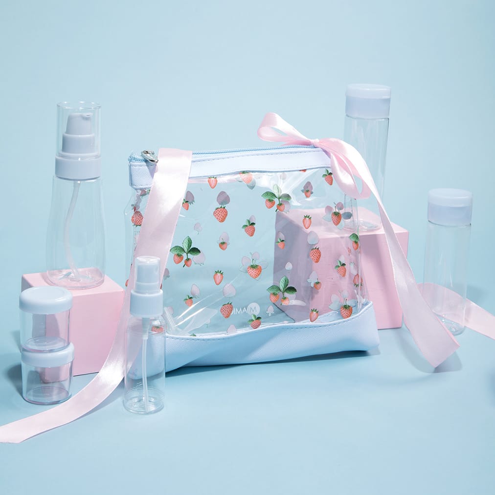 The transparent pouch with strawberry pattern is adorned with a pink ribbon. Soft blue topped jars and bottles come with this travel bag set.